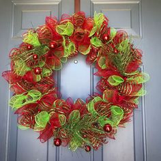 a red and green christmas wreath hanging on a door