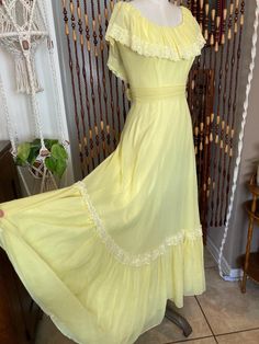 1970's beautiful butter yellow prairie dress with ruffle hem. Corseted bodice, detachable waist tie, zip and hook closure. There is no tag. Classic 70's poly-cotton fabric with acetate lining. Feels like soft cotton gauze. It is fully lined. There are some small holes and some thread pulls, almost impossible to notice with the miles and miles of fabric. No giant stains or tears. It is VERY snug on the size 8 dress form. I would say this is a solid modern size 6, maybe a small 8 depending on your waist. But please compare your measurements below: Bust 34 inches  Waist 26.5 inches  Hips FREE Length 56 inches Cottagecore Maxi Dress With Ruffles For Daywear, Vintage Ruffled Maxi Dress For Spring, Spring Vintage Maxi Dress With Empire Waist, Summer Prairie Dress With Empire Waist And Ruffles, Vintage Ruffle Maxi Dress For Spring, Prairie Style Ruffle Dresses For Daywear, Vintage Empire Waist Maxi Dress For Spring, Summer Vintage Dress With Empire Waist, Fitted Summer Prairie Dress With Ruffle Hem