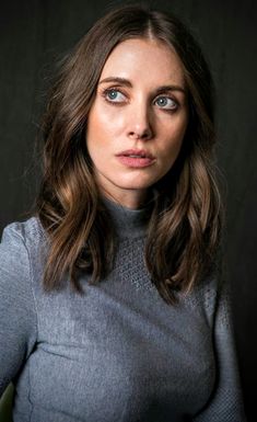 a woman with long hair and blue eyes is posing for a studio photo in front of a black background