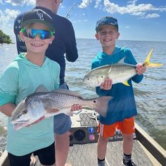 two boys on a boat with fish in their hands and one boy wearing sunglasses holding the same fish