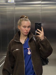 a woman taking a selfie with her cell phone in front of an escalator