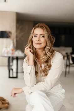 a woman sitting on the floor with her hand under her chin and looking at the camera