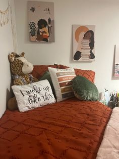 there is a bed with orange sheets and pillows on the headboard, next to pictures hanging on the wall