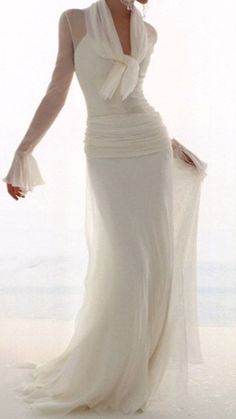 a woman in a white dress is standing on the beach