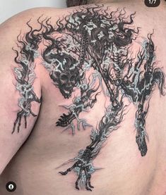 the back of a man's shoulder with tattoos on it and an image of a demon