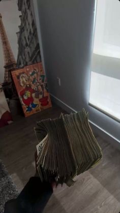 a stack of books sitting on top of a hard wood floor next to a window