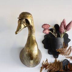 two vases with flowers in them are next to a wall mounted duck and fern