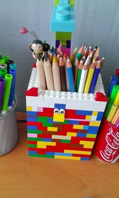 several pencils and markers are sitting in a lego box next to a soda can