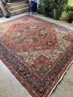 an old rug is laying on the ground in front of some stairs and potted plants