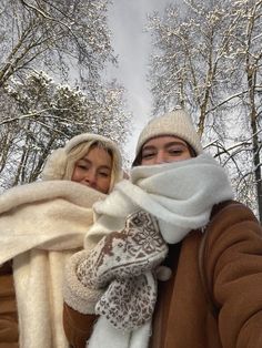 two people standing in the snow with scarves on