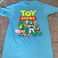 a blue toy story t - shirt laying on the floor