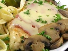 a white plate topped with pasta and meat covered in sauce, mushrooms and parsley