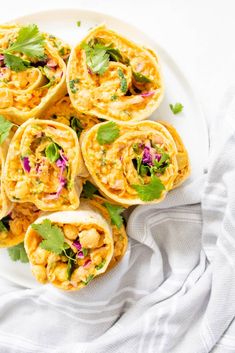 a white plate topped with burritos filled with meat and vegtables