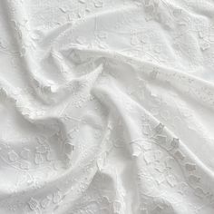 an image of white fabric textured with flowers and leaves on the surface, closeup