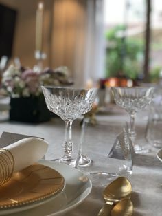 the table is set with silverware and gold place settings for two people to sit at