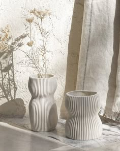 two white vases sitting next to each other on a table