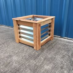 a wooden box with an air vent on the top and bottom, sitting in front of a blue wall