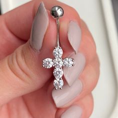 a close up of a person's hand holding a piercing with a cross on it