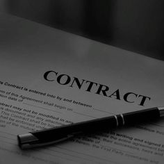 a pen sitting on top of a paper with the word contract written in black and white