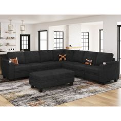 a living room with a large black sectional couch and footstool on the rug