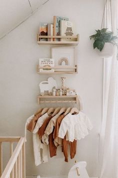 a baby's room with white walls and wooden shelves filled with clothes, toys and books