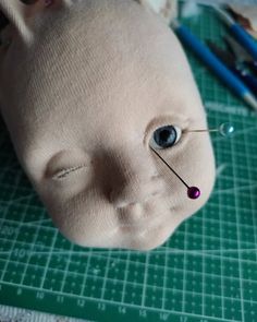 a close up of a stuffed animal head on a table with scissors and pencils