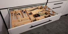 an open drawer with utensils and spoons in it