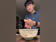 a man is mixing something in a bowl with his hands on top of the bowl