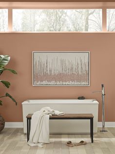 a white bench sitting in front of a window next to a potted plant on top of a hard wood floor