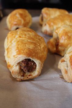 several pastries sitting on top of a piece of wax paper covered in meat and cheese