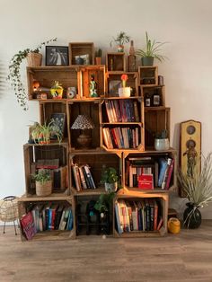 the bookshelf is made out of wooden crates with plants in them and other items on top