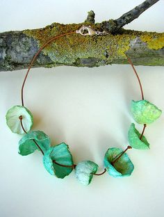 a necklace made with green leaves on a branch