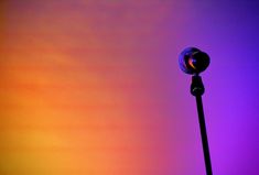 a street light in front of an orange and purple sky