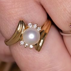 This romantic ring features a lustrous pearl accented by diamonds in a dynamic bypass design. The high quality diamonds add bright sparkle to the sweet romance of the pearl. The effect is an air of grace and timeless elegance. This beauty would make an excellent anniversary gift or a beautiful treat for yourself!The pearl is spherical and has beautiful luster. It is securely attached to the setting. The diamonds are all brilliantly white, graded G for color. They are all completely eye clean, gr Anniversary Akoya Pearl Ring With Diamond Accents, Akoya Pearl Ring With Diamond Accents For Anniversary, Timeless Pearl Ring With Diamond Accents For Anniversary, Timeless Anniversary Pearl Ring With Diamond Accents, Timeless Diamond Pearl Ring For Anniversary, Exquisite Pearl Ring With Diamond Accents For Anniversary, Fine Jewelry Pearl Ring With Diamond Accents For Anniversary, Elegant Diamond White Bypass Ring For Anniversary, Fine Jewelry Brilliant Cut Pearl Ring For Anniversary