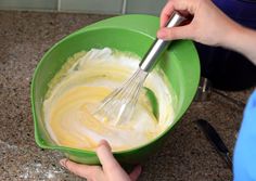 someone mixing batter in a green bowl with a whisk