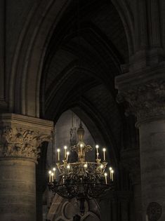 a chandelier hanging from the ceiling in an old building with columns and arches