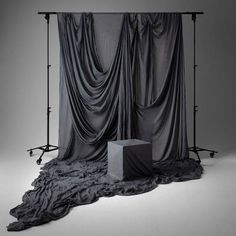 a black and white photo of a curtained backdrop in front of a square object