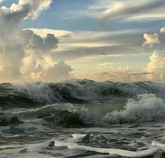 an ocean with waves crashing and clouds in the sky