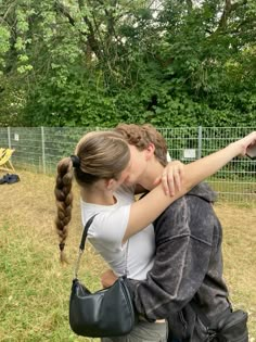 two people sitting on the ground in front of a fence and one person holding a bird