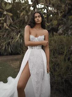 a woman in a white dress posing for the camera with her legs crossed and one leg bent