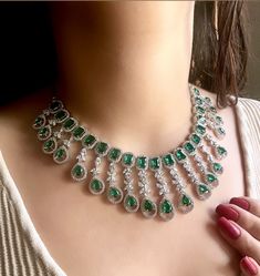 Add a touch of glamour and sophistication with this high quality necklace set in beautiful  emerald green stones. The stones in this set bling and look close to the real thing. This set is sure to make heads turn!  It features an adjustable necklace and a pair of earrings. It can be paired perfectly with both ethnic and western outfits. Length :14 inches Width: 8 inches Adjustable length with a metal chain at the back Earrings length: 2.5 inches Each earring weighs: 12 gms  Closure: Pushback Ite Emerald Kundan Necklace For Weddings, Bollywood Bridal Necklace With 17 Green Jewels, Emerald Stone Necklaces For Weddings, Hand Set Emerald Necklace For Wedding, Hand Set Emerald Necklace For Reception, Hand-set Emerald Necklace For Weddings, Emerald Jewel Bridal Necklace For Wedding, Wedding Emerald Necklace Hand Set, Green Cubic Zirconia Bridal Necklace For Reception