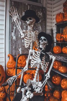 two skeletons sitting in front of pumpkins