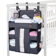 a baby crib with several diapers and blankets in the bottom section, hanging from it's side