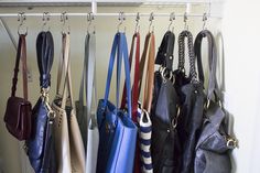 several purses hanging from hooks in a closet