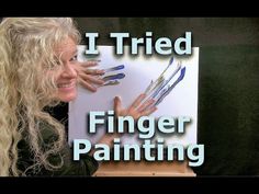 a woman with long blonde hair holding up her finger painting