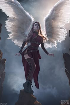 a woman with white wings standing on top of a rock