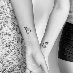 two people holding hands with butterfly tattoos on their arms