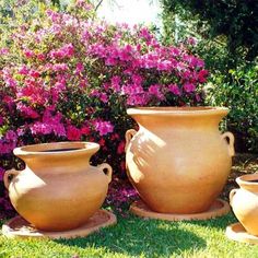 three large vases are sitting in the grass