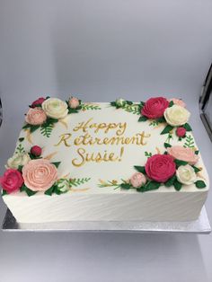 a white cake with pink and yellow flowers on it that says happy retirement suse