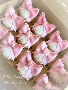 pink and white cupcakes in a box with bows on them are ready to be eaten